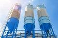 Large blue industrial tanks for cement, sand, water. Blue sky background with white clouds. Bottom view Royalty Free Stock Photo