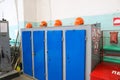 Large blue metal iron workwear lockers with protective building helmets in the locker room at an industrial plant