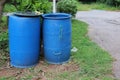 A large blue round plastic bin is located on the village road for dumping and sorting waste.