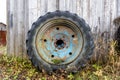 a large blue rusty wheel from a tractor stands near the wall of the barn Royalty Free Stock Photo