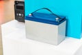 Large blue and silver battery pack on a white pedestal, possibly in an exhibition setting Blurred background suggests additional Royalty Free Stock Photo