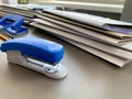 A large blue stapler for stapling paper lies next to the folders of documents on the working business desk in the office. Royalty Free Stock Photo