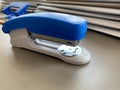 A large blue stapler for stapling paper lies next to the folders of documents on the working business desk in the office. Royalty Free Stock Photo