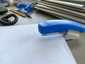 A large blue stapler for stapling paper lies next to the folders of documents on the working business desk in the office. Royalty Free Stock Photo