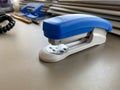 A large blue stapler for stapling paper lies next to the folders of documents on the working business desk in the office. Royalty Free Stock Photo