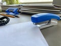 A large blue stapler for stapling paper lies next to the folders of documents on the working business desk in the office. Royalty Free Stock Photo