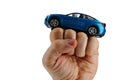 Large blue SUV car model placed on raised fist of adult man, white background. Royalty Free Stock Photo