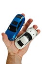 Large blue SUV and white supersport car models held in left palm of adult man, white background Royalty Free Stock Photo