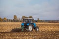 Large blue tractor plow plowed land after harvesting the maize crop on a sunny, clear, autumn day. Royalty Free Stock Photo