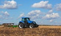 A large blue tractor, plowing field against the beautiful sky. Royalty Free Stock Photo