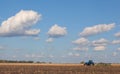 A large blue tractor, plowing field against the beautiful sky. Royalty Free Stock Photo