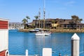 A large boat with tall masts docked in the deep blue ocean waters of Dana Point Harbor surrounded by buildings