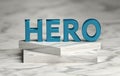 Large bold blue word HERO standing on marble pedestal