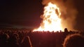 Large bonfire with sparks at twilight with people gathered around. Walpurgis Night Bonfire