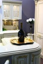 Large bottle with red wine and two glasses on golden plate in white rustical luxurious kitchen interior