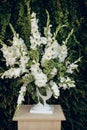 A large bouquet of flowers and leaves in a white vase on the table, as a decoration for a wedding ceremony Royalty Free Stock Photo