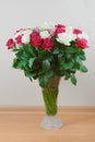 A large bouquet of red, pink and white roses in a glass vase on the floor. Congratulations on the holiday.