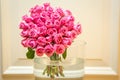 Large bouquet of two dozen pink roses in large glass vase