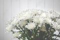 Large bouquet of white chrysanthemums with green stalks stands against a white wooden wall Royalty Free Stock Photo