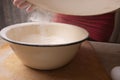 Large bowl, cutting board, sieve for sifting flour on the table. Female hands sifting flour in the home kitchen