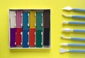 A large box with twelve pieces of plasticine of different colors and clay stacks on a yellow Royalty Free Stock Photo