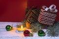 Boxes with gifts, Christmas tree decorations, a spruce branch and a burning candle on a festive red and white background Royalty Free Stock Photo