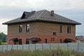 A large brick brown house with windows behind a gray concrete fence in green grass Royalty Free Stock Photo