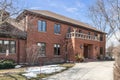 A large brick home with a wrap around driveway.