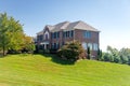 Large brick house with a green lawn side view. Landscape on a summer sunny day