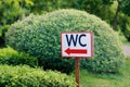 Large bright sign indicating the toilet WC in a green beautiful park