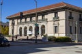 A large brown building with a red brick roof on the corner of Colorado Blvd and Garfield Ave with people walking and cars driving