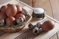 Large brown chicken eggs and motley quail eggs lie on straw in a wicker basket on a wooden table Royalty Free Stock Photo