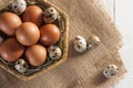 Different eggs in basker and on burlap. White wooden background.