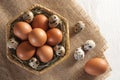 Many different eggs in basket and on burlap. View from above.