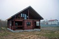 Large brown unfinished wooden house in dry grass