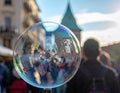 Large bubble reflects a blurred city scene with building sky and people Royalty Free Stock Photo