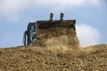 Large bucket with an escalator pouring soil frontally on a sunny hot day against the sky. Global construction