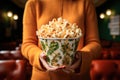 Large bucket of popcorn in the hands of a woman in a movie theater close-up