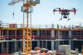 Large Building Under Construction With Red and Black Remote Control Helicopter Flying, An open construction site fully operated by Royalty Free Stock Photo