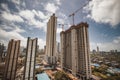 Large buildings with construction cranes under a blue sky with clouds in Mumbai city, India.