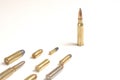 A large bullet 7.62 x 51mm NATO standing in front of several other bullets laying over a white surface