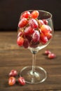 A large bunch of ripe grapes in a glass on the background of a dark textured wooden table. Grapes in a wine glass close-up and cop Royalty Free Stock Photo