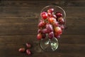 A large bunch of ripe grapes in a glass on the background of a dark textured wooden table. Grapes in a wine glass close-up and cop Royalty Free Stock Photo