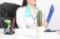 A large cactus stands against the background of a doctor wearing a glove. The concept of rectal pain, hemorrhoids, anal