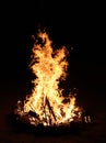 A large campfire in the center of the camp at night.