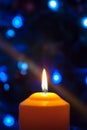 A large candle burns against the background of a garland with shining lights. Vertical photo, defocus. Mystic esoteric romance