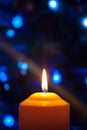 A large candle burns against the background of a garland with shining lights. Vertical photo, defocus. Mystic esoteric