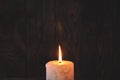 A large candle burns in the darkness on a wooden texture background Royalty Free Stock Photo