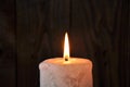 A large candle burns in the darkness on a wooden texture background Royalty Free Stock Photo