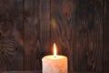 A large candle burns in the darkness on a wooden texture background Royalty Free Stock Photo